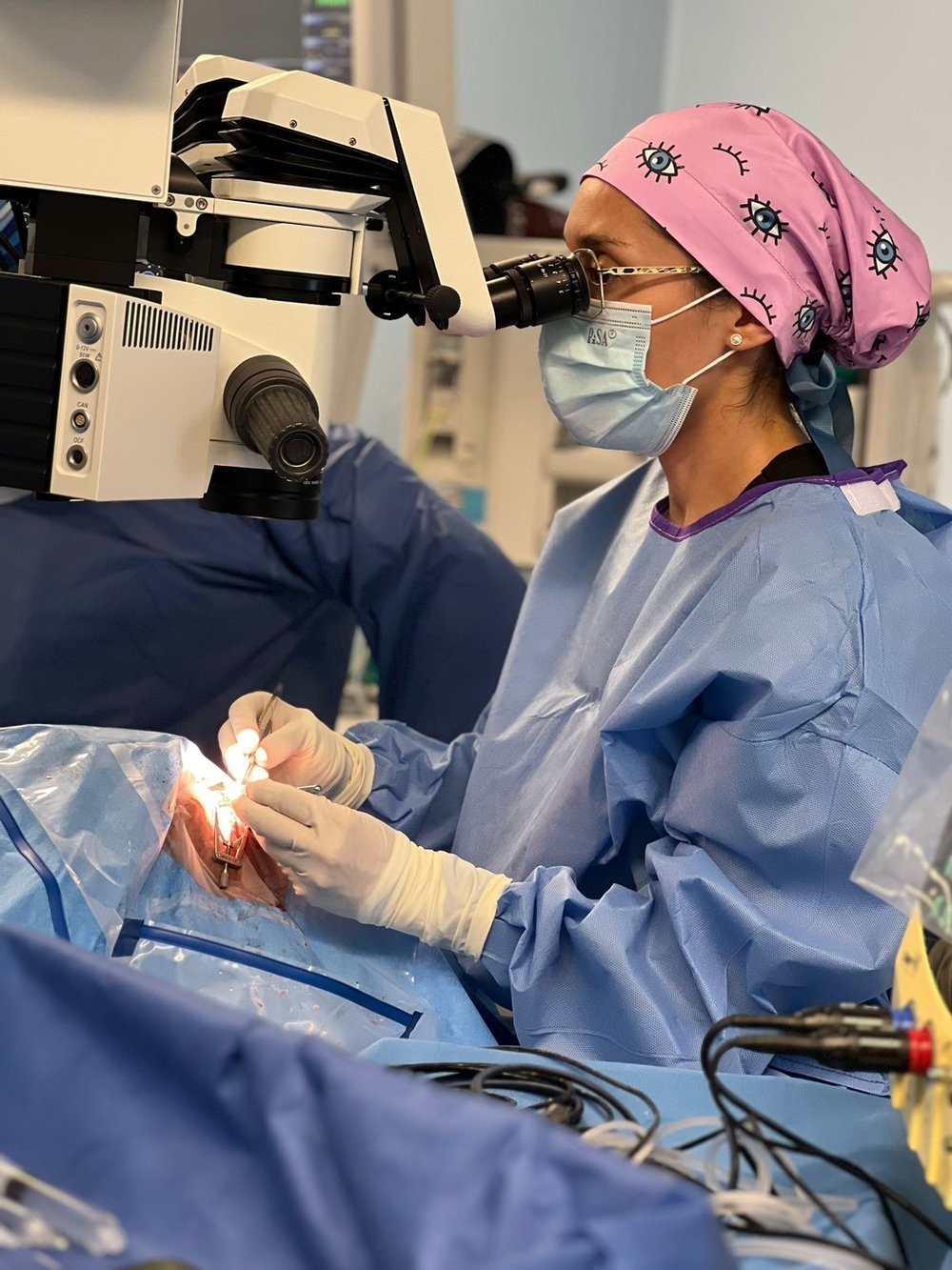 La Dra. Kristell Cantón enfocada en el microscopio durante una cirugía